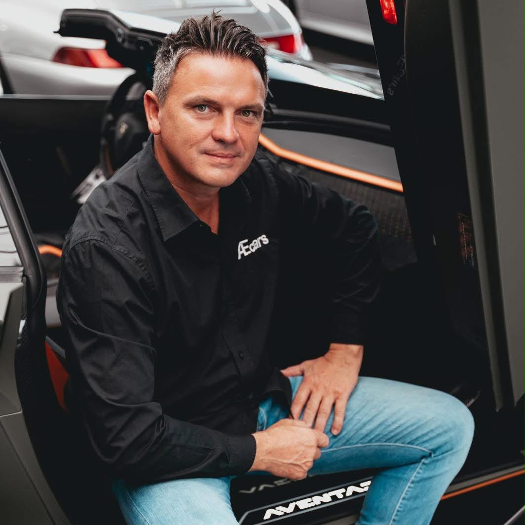 Alexander, zaakvoerder van AEcars, bij een exclusieve sportwagen